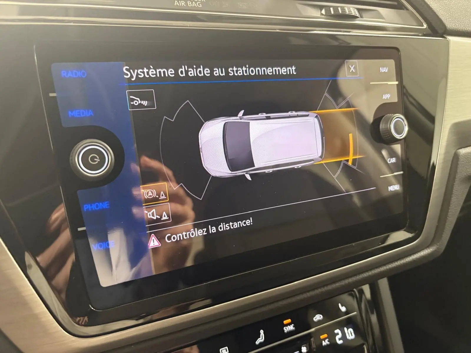 Écran tactile intérieur du Volkswagen Touran 2025 affichant le système d'aide au stationnement avec alertes de distance.