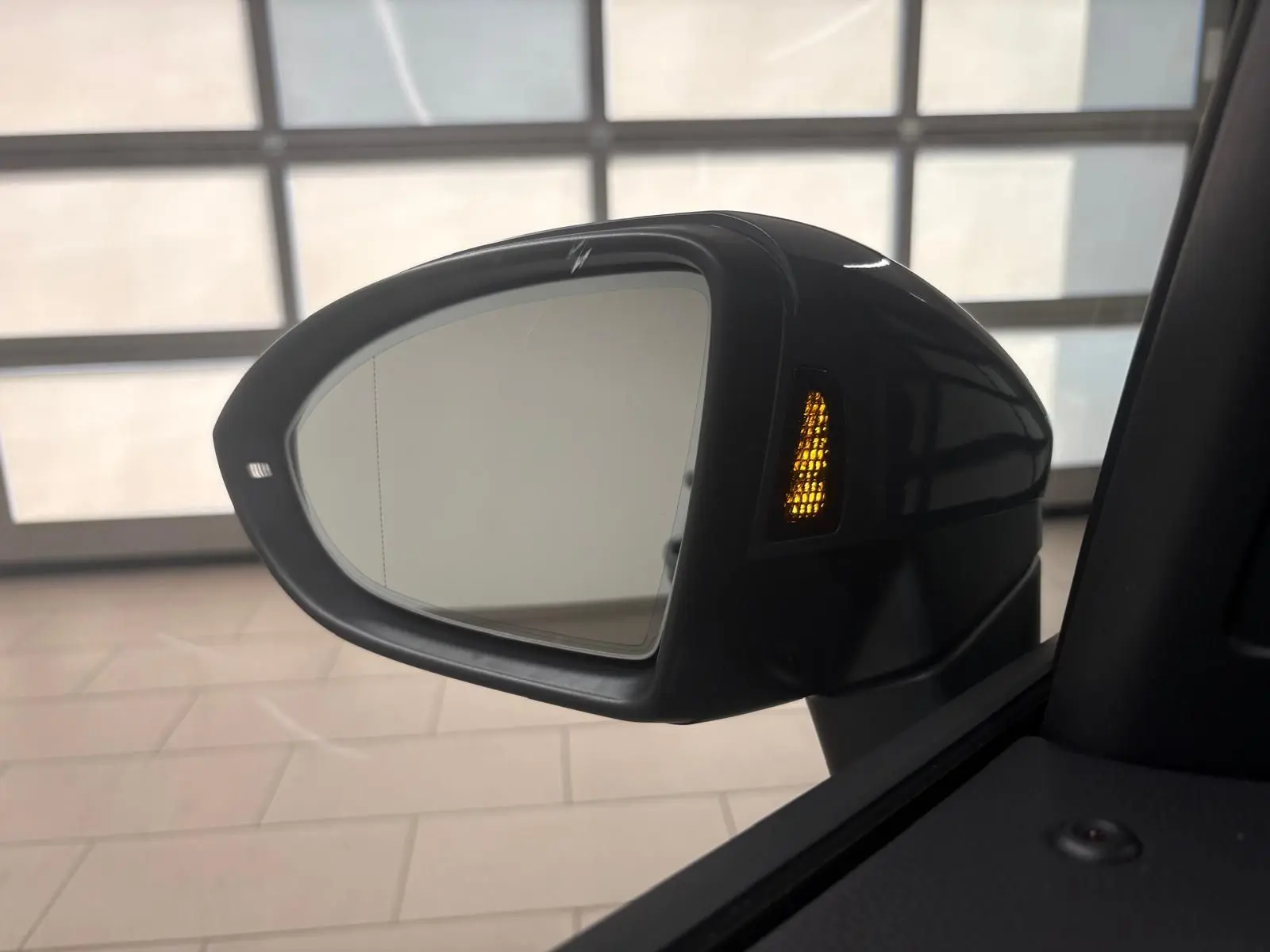 Rétroviseur extérieur droit du Volkswagen Touran gris dauphin 2025 avec clignotant orange allumé et angle intérieur visible.