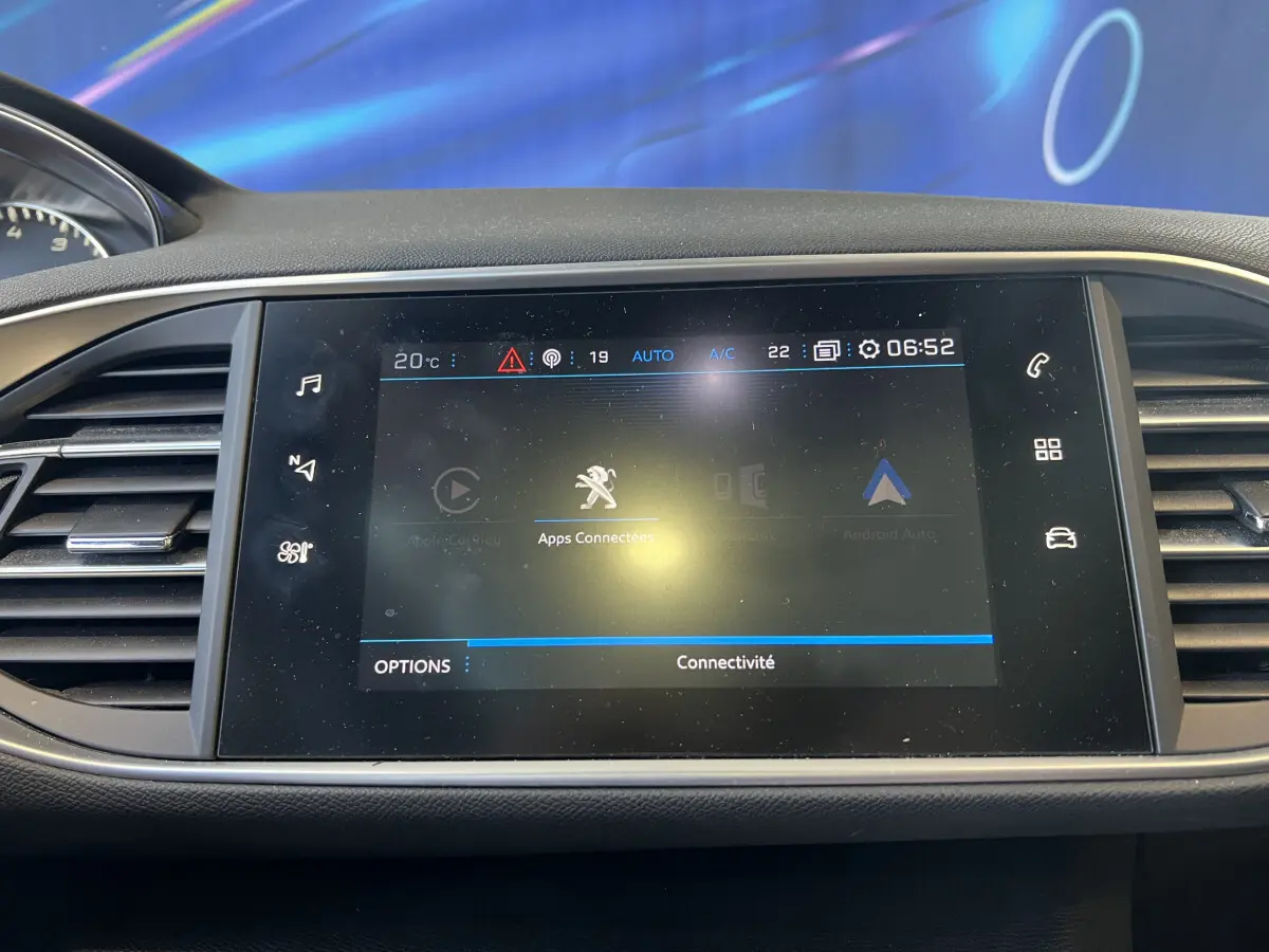 Écran tactile central affichant les applications connectées dans l'habitacle d'une Peugeot 308 rouge de 2019.