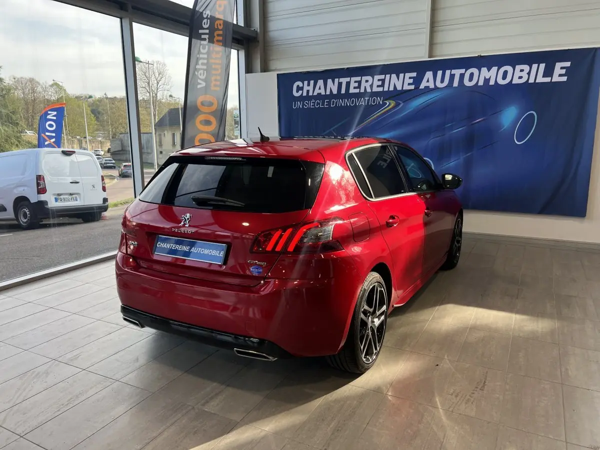 PEUGEOT 308 Puretech rouge vue 3/4 arrière droit en showroom avec feux arrière LED et jantes alliage noires.
