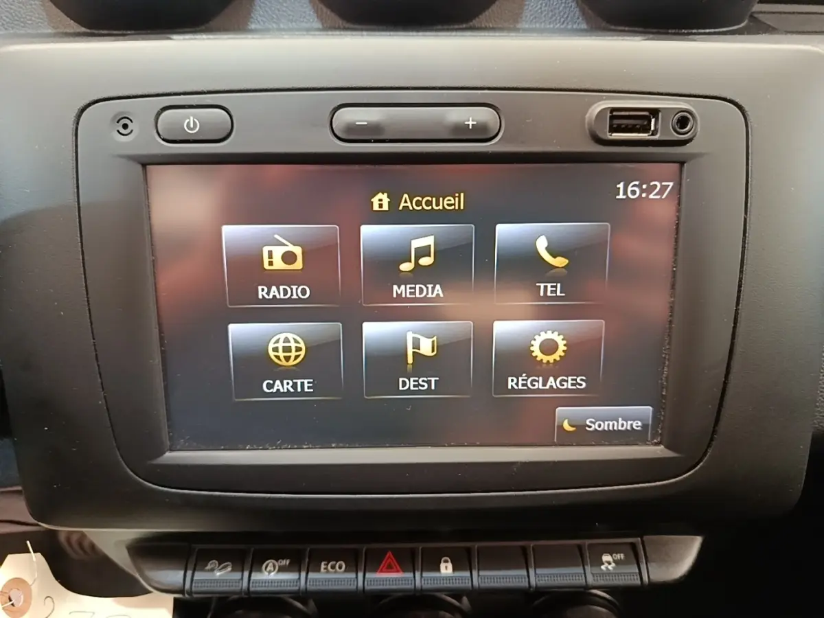 Écran tactile central du tableau de bord du Dacia Duster blanc, affichant le menu principal multimédia.