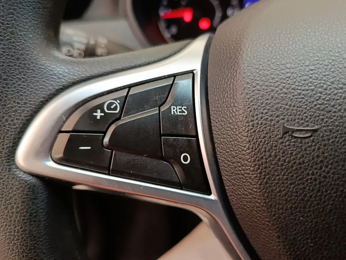 Gros plan sur les commandes du volant cuir synthétique du Dacia Duster 2021, boutons multifonctions visibles.