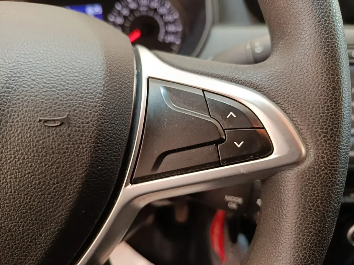 Gros plan sur les commandes du volant cuir synthétique du Dacia Duster 2021, boutons de réglage multifonctions visibles.