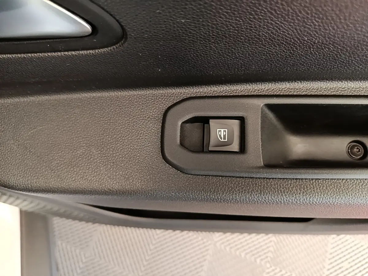 Gros plan sur le bouton de commande de la vitre électrique côté conducteur du Dacia Duster blanc, intérieur noir.
