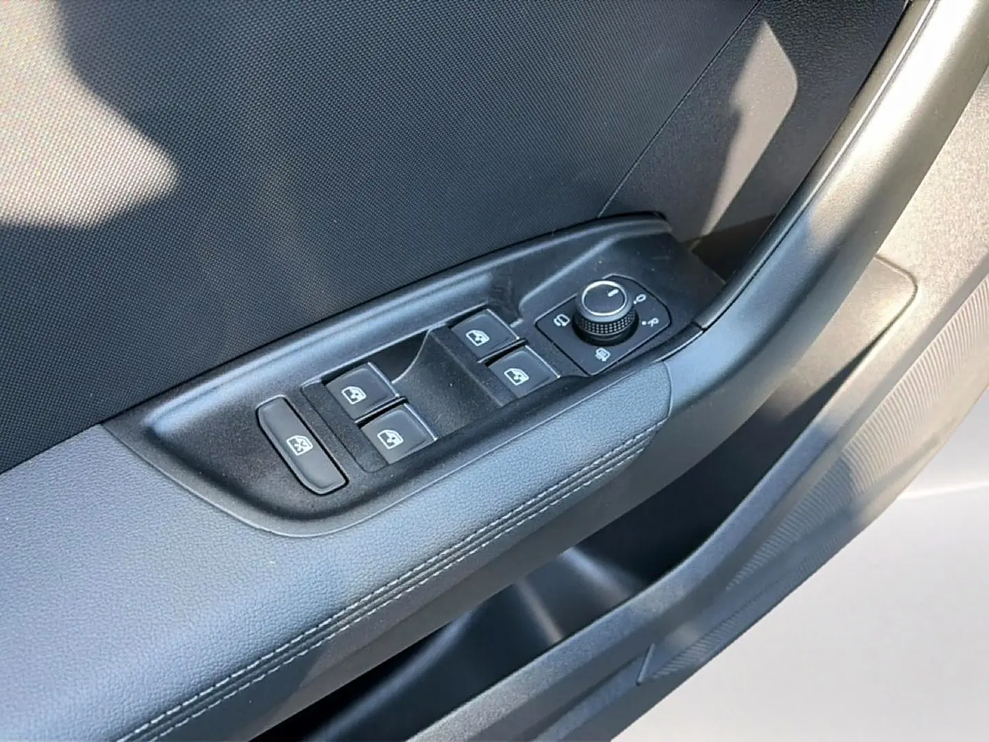 Gros plan sur les commandes de lève-vitres et rétroviseurs côté conducteur de l'Audi A1 Sportback blanc et noir.