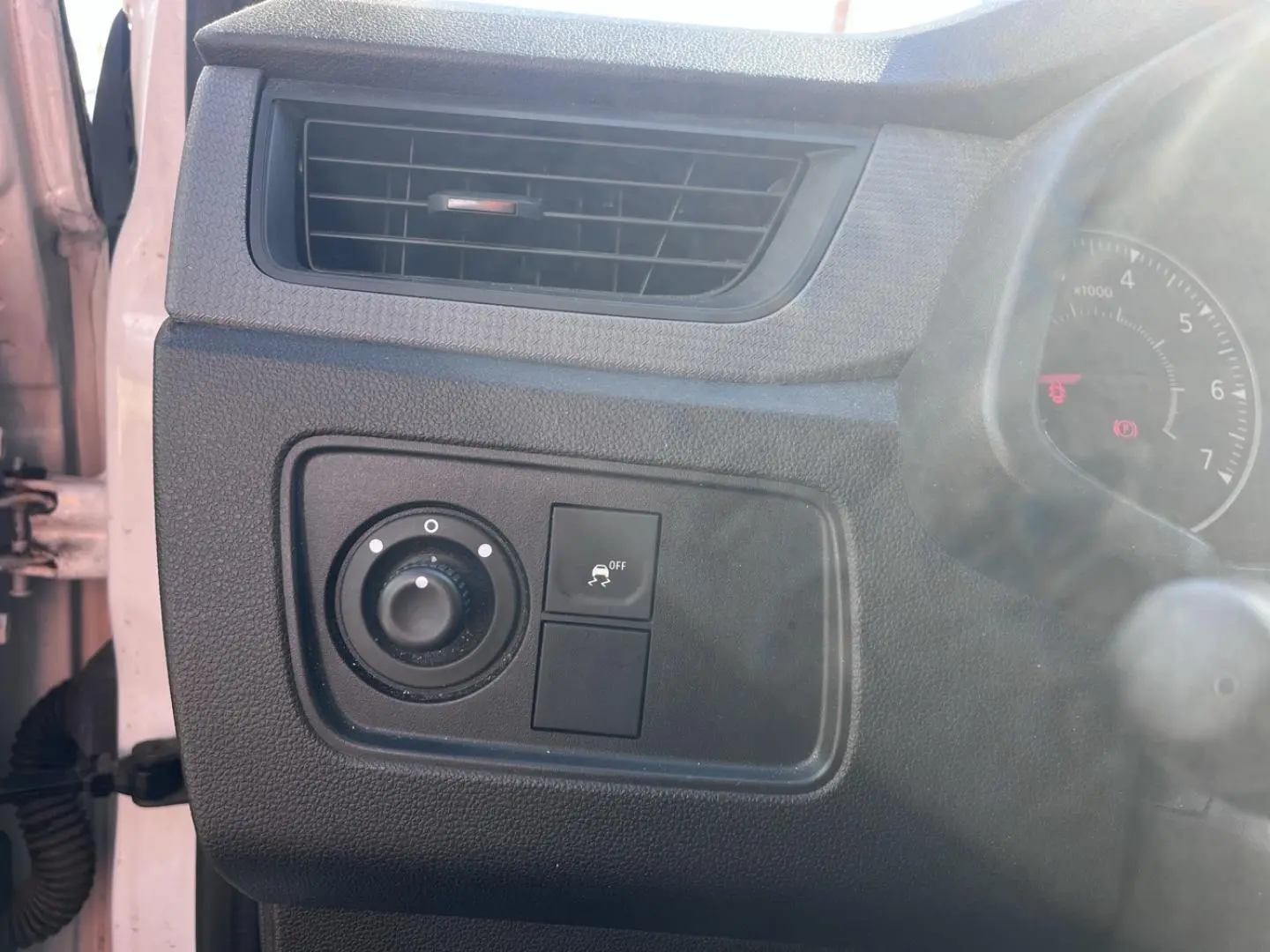 Détail du tableau de bord noir côté gauche avec commande des phares et bouton de désactivation de l'ESP sur Renault Express Van blanc.