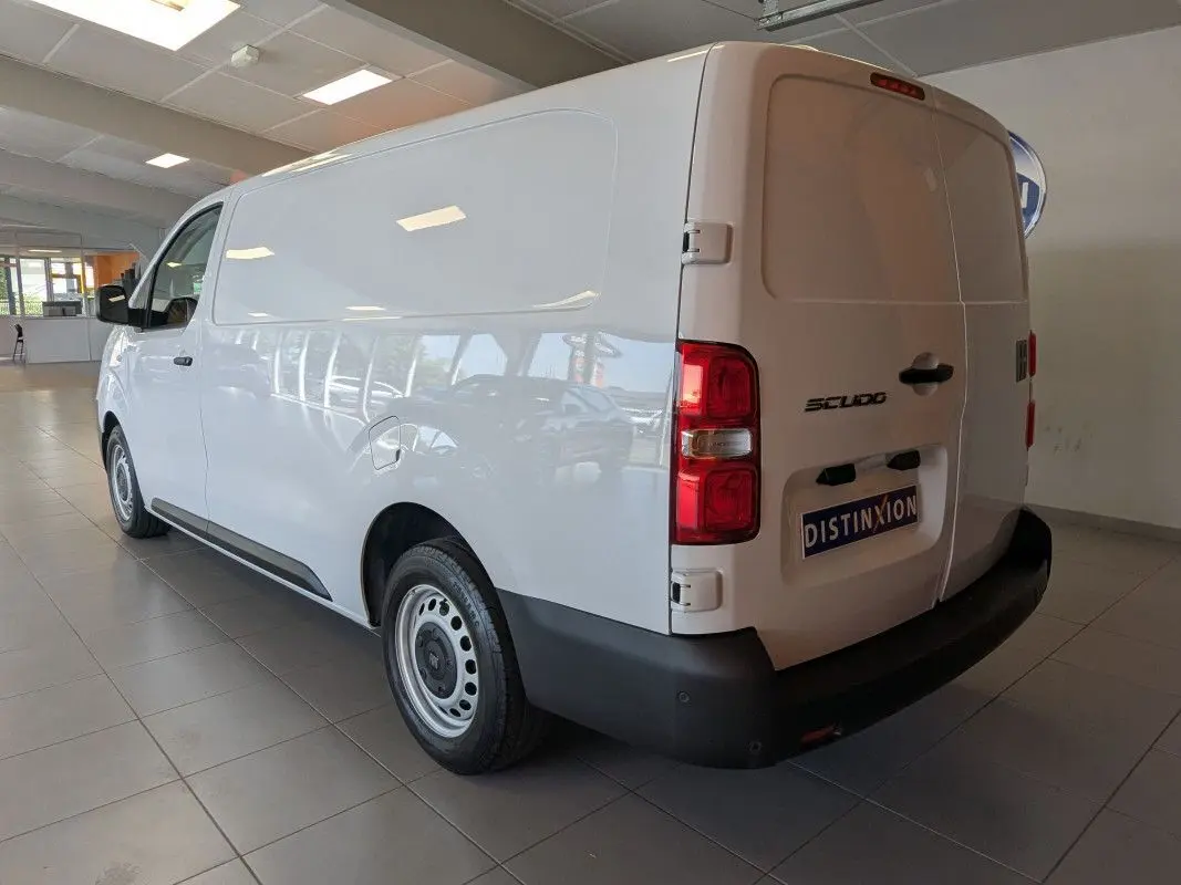 Vue 3/4 arrière droite d’un FIAT Scudo Fourgon blanc, avec portes arrière fermées et jantes tôles grises 17 pouces.