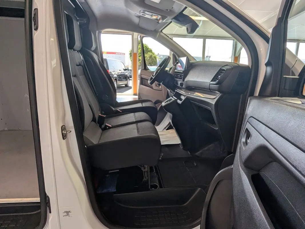 Vue intérieure côté conducteur du Fiat Scudo Fourgon blanc 2025, montrant les sièges avant et le tableau de bord moderne.