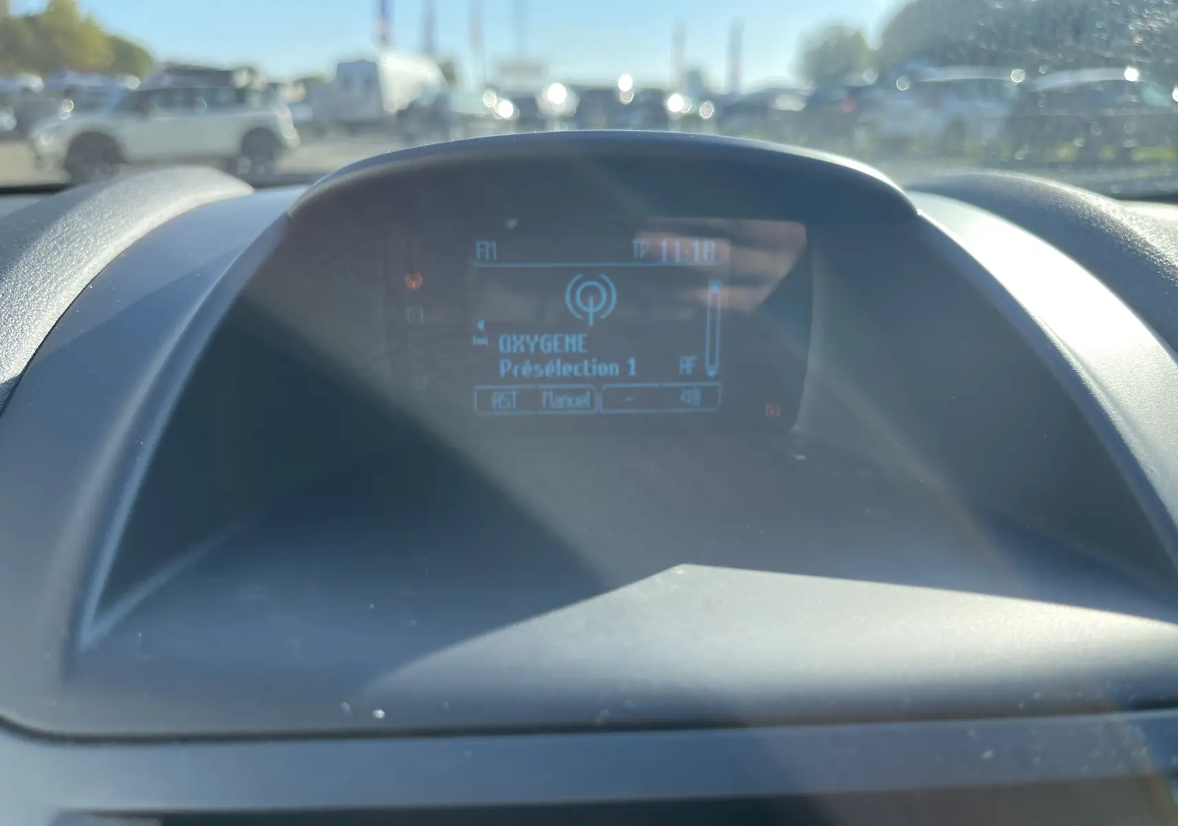 Écran central du tableau de bord de la Ford Fiesta 2014 affichant la radio Oxygène en extérieur lumineux.