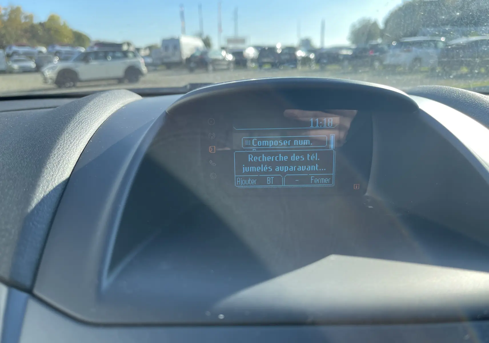 Écran central du tableau de bord d'une Ford Fiesta 2014 gris titane affichant le menu Bluetooth en extérieur ensoleillé.