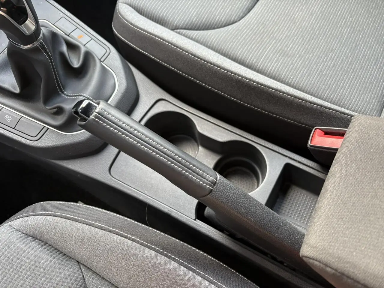 Vue rapprochée de la console centrale de la SEAT IBIZA blanche 2025, montrant frein à main cuir et sièges gris.