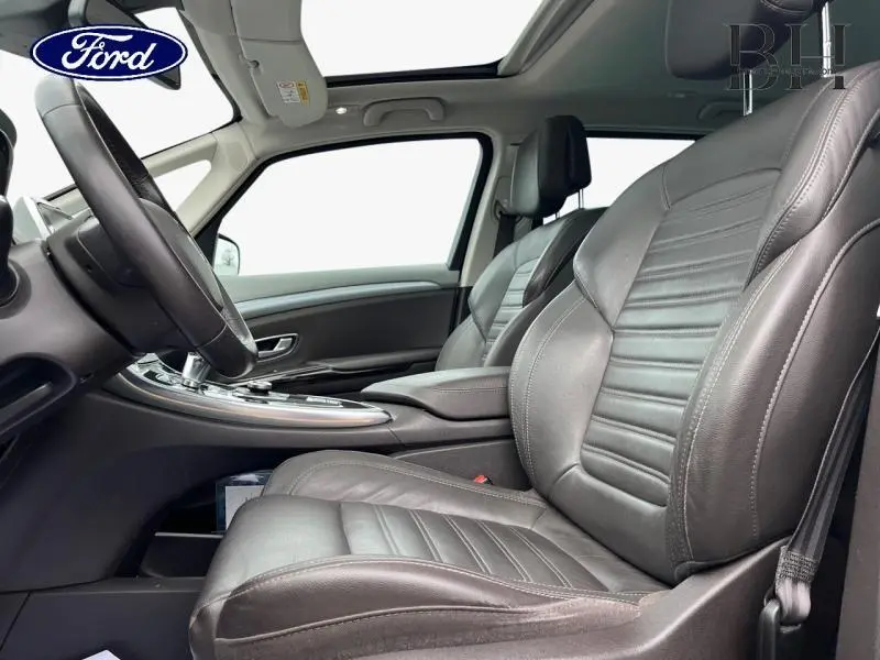 Vue intérieure côté conducteur montrant les sièges en cuir brun foncé et le toit ouvrant panoramique du Renault Espace gris Cassiopée.