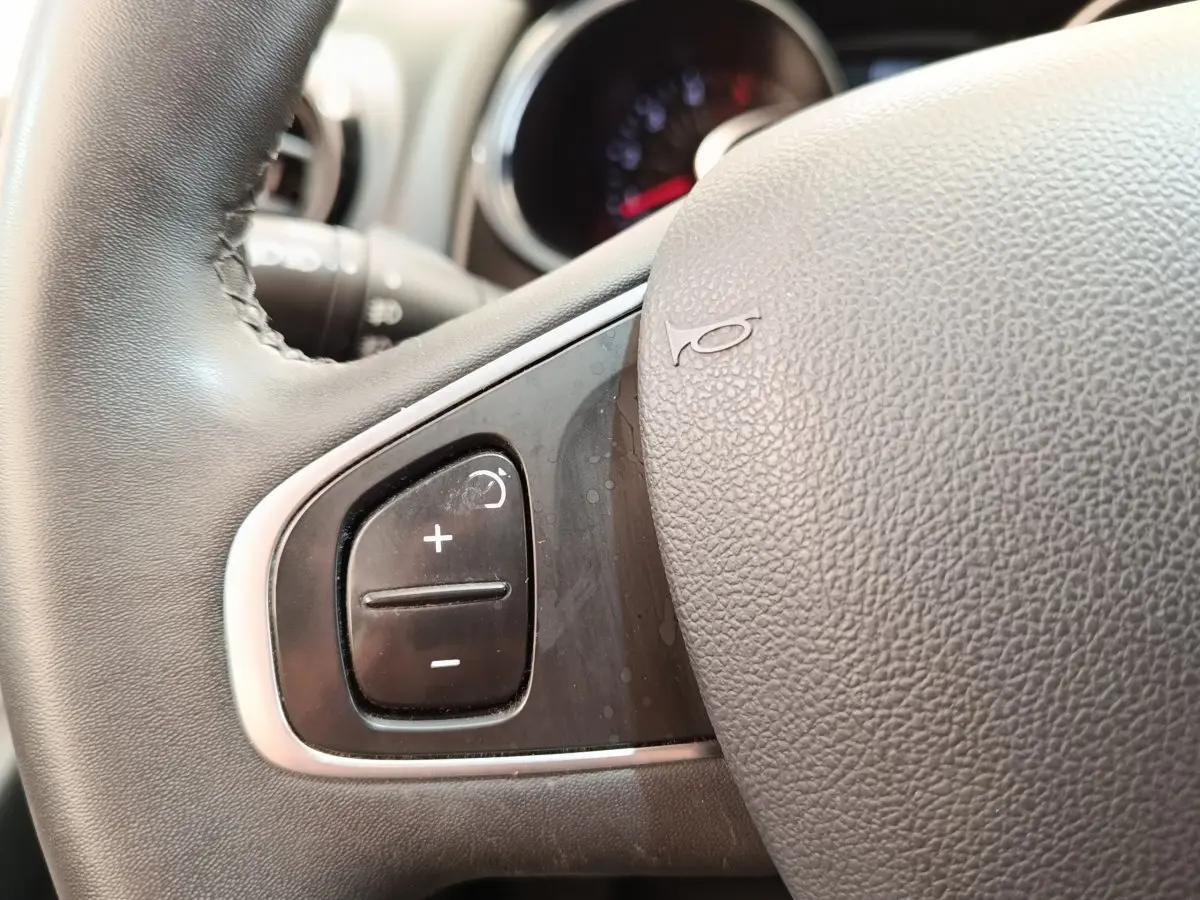 Gros plan sur le volant cuir noir de la Renault Clio Business dCi 75, montrant les commandes de régulateur de vitesse.