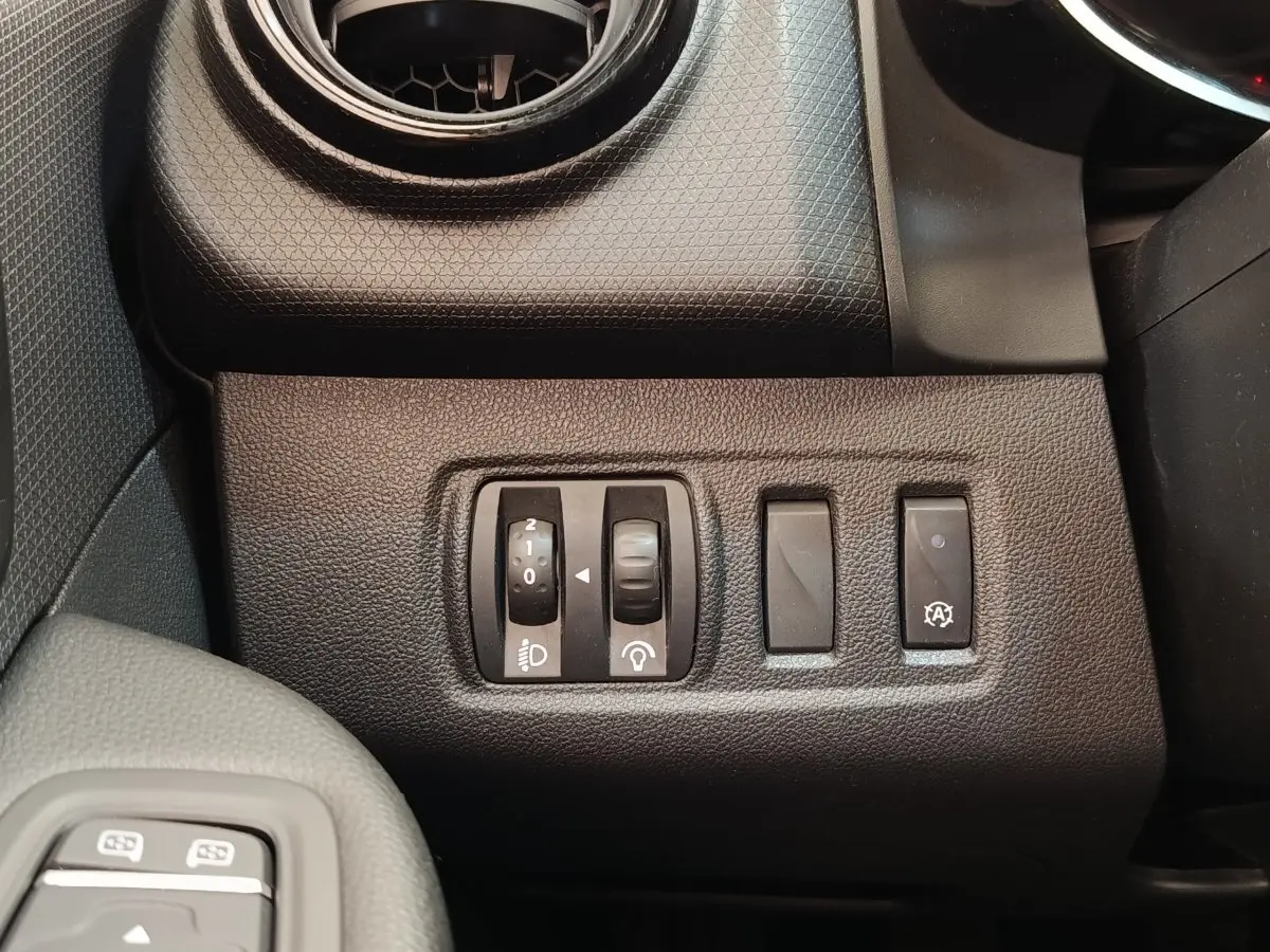Gros plan sur les commandes de réglage des phares et fonction arrêt auto du moteur, tableau de bord noir Renault Clio 2018.