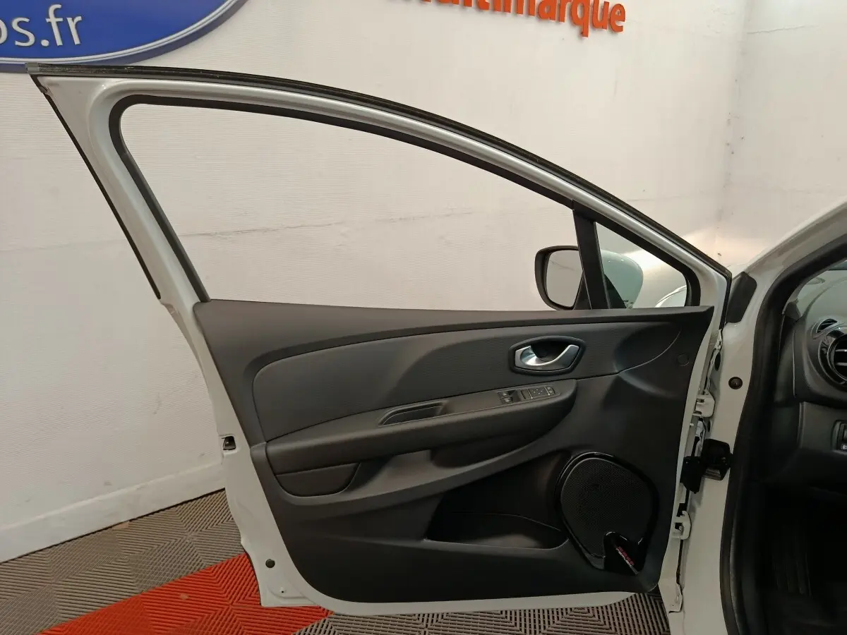 Vue côté gauche de la porte avant blanche ouverte d'une Renault Clio Business 2018, intérieur noir avec commandes électriques.