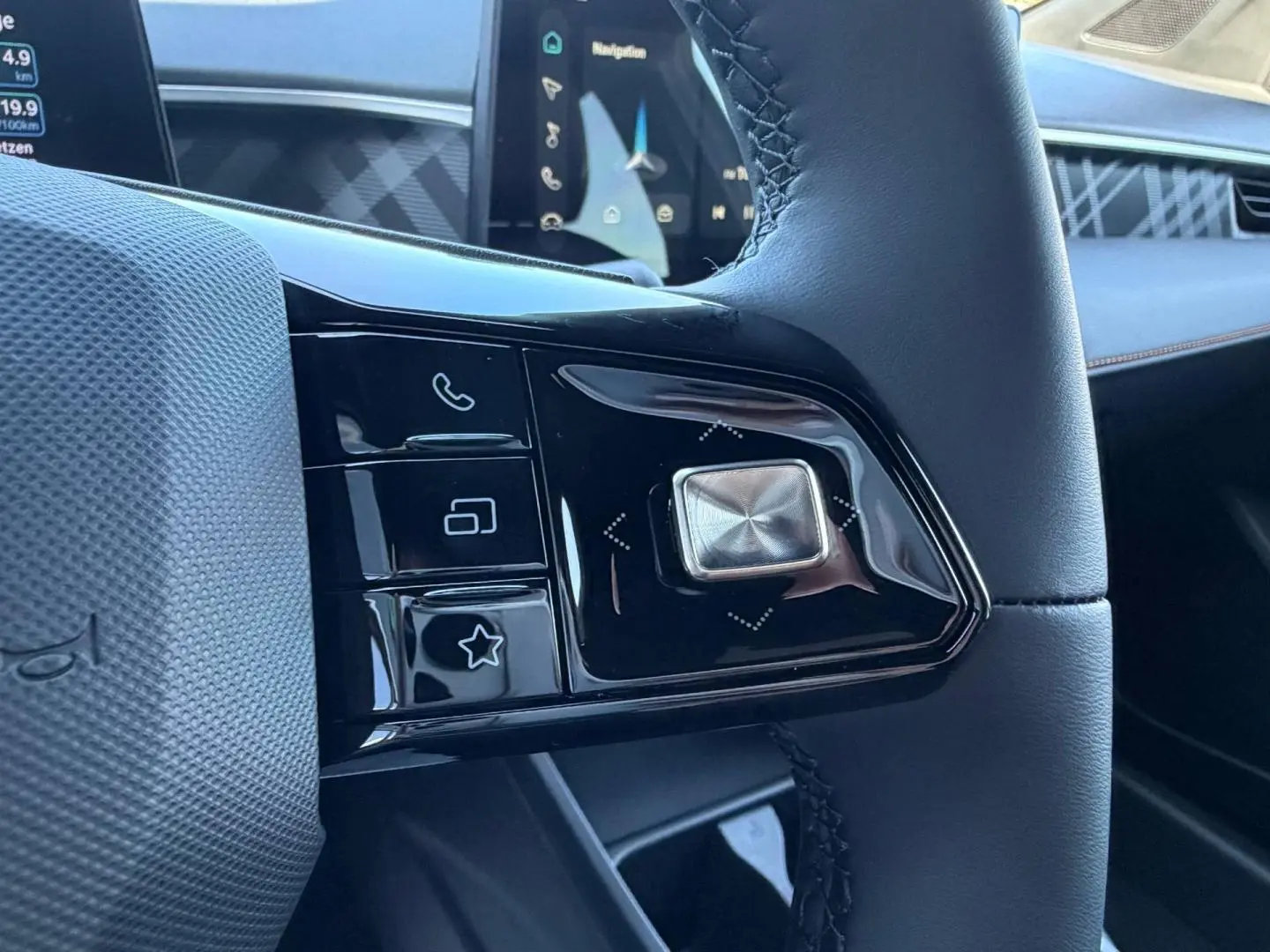 Gros plan sur les commandes noires brillantes du volant cuir noir du MG3 1.5 Hybrid+ Pebble Black, avec écran tactile en arrière-plan.