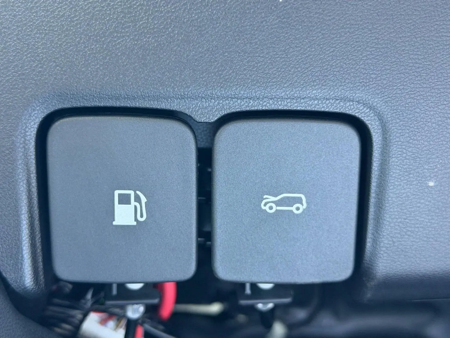 Gros plan sur les boutons d'ouverture de trappe à carburant et de coffre dans l'habitacle du MG3 Pebble Black.