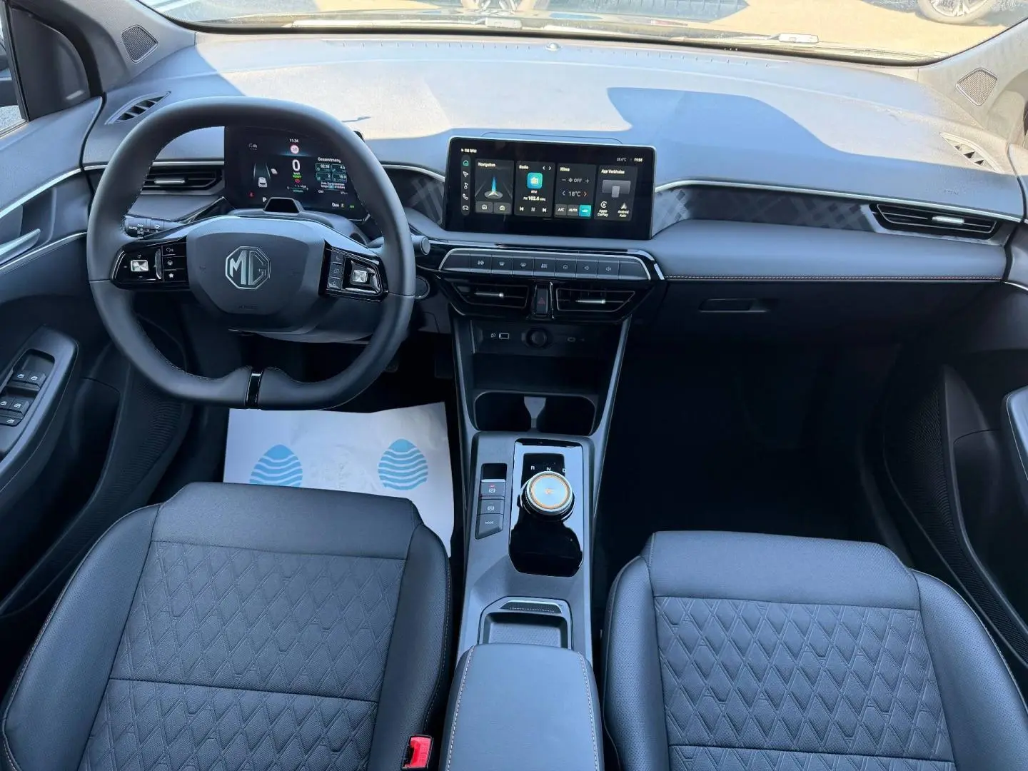 Vue intérieure avant du MG3 1.5 Hybrid+ 195ch Luxury avec tableau de bord moderne et sièges en similicuir noir.