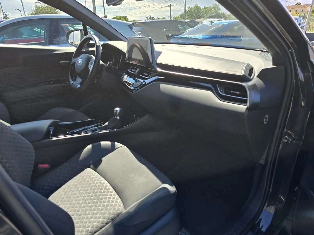 Intérieur côté passager du Toyota C-HR noir métal 2023, avec tableau de bord moderne et sièges tissu/cuir embossés.