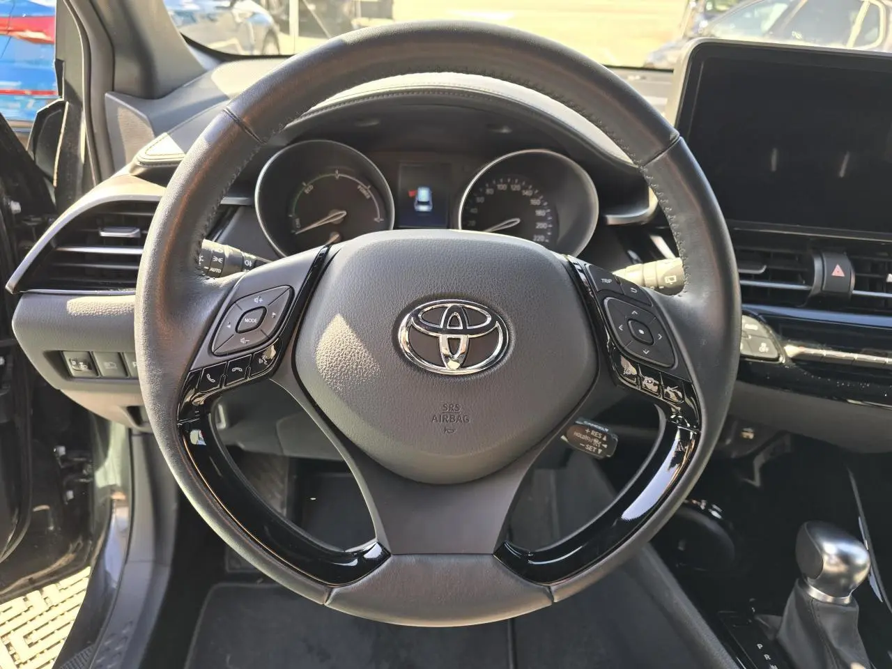 Volant cuir noir multifonction de Toyota C-HR 1.8 Hybride 2023 vu de face avec tableau de bord et écran tactile.
