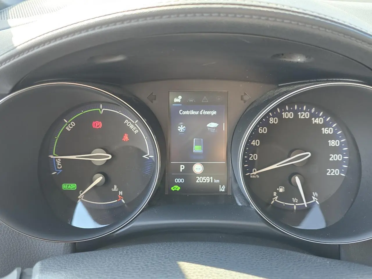 Tableau de bord du Toyota C-HR hybride 2023 avec écran central et compteurs analogiques en vue frontale.