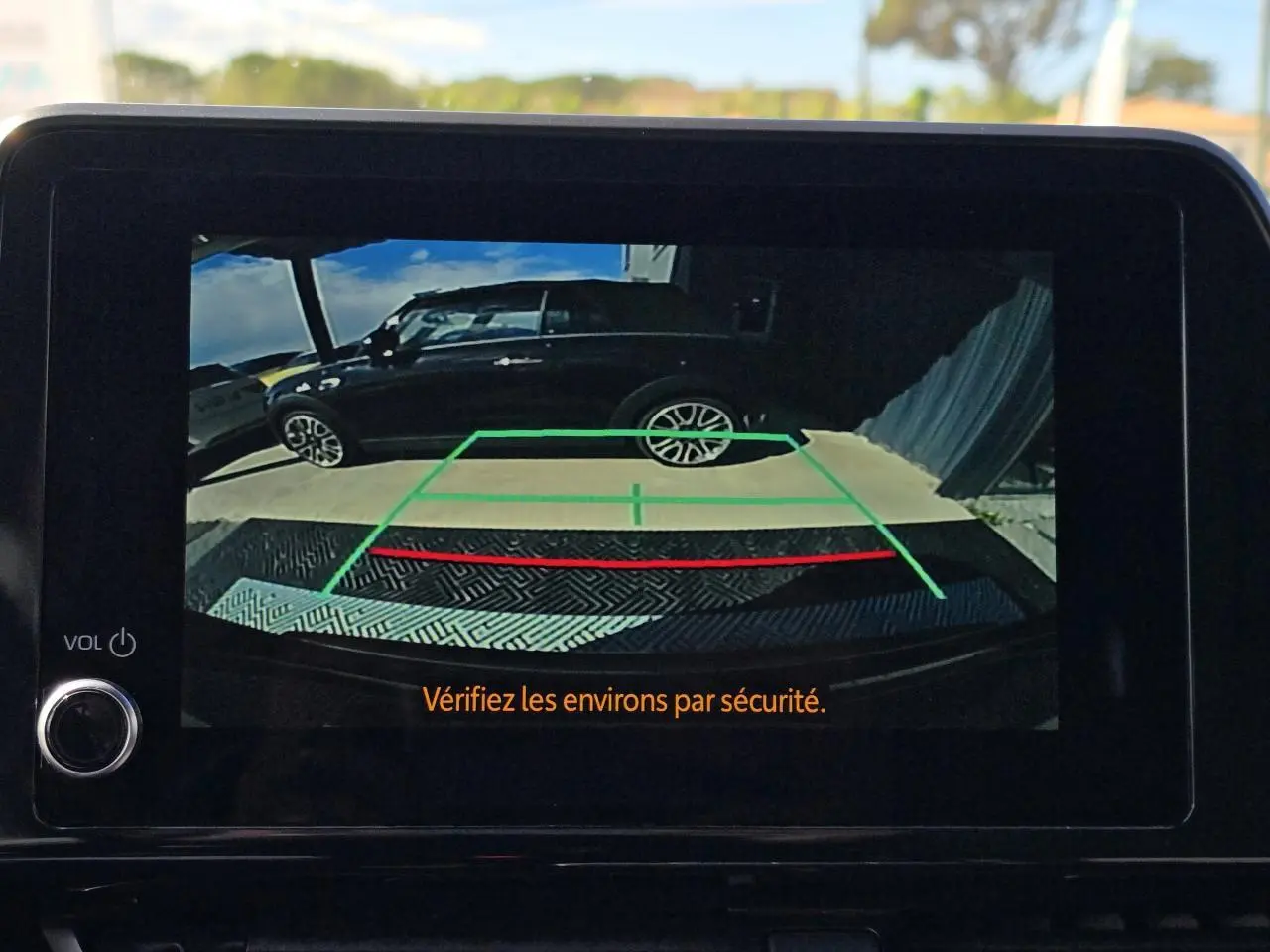 Vue latérale droite du Toyota C-HR 1.8 Hybride 2023 noir métal, affiché sur l'écran de la caméra de recul.