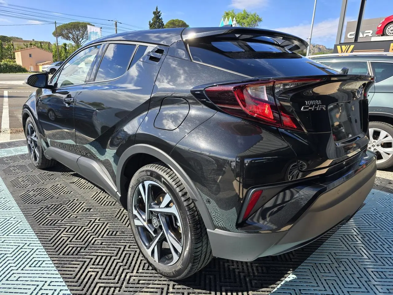 Toyota C-HR noir métal en 3/4 arrière droit, avec jantes alliage 18 pouces et becquet avant couleur carrosserie.