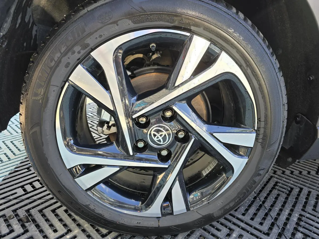 Gros plan sur la jante alliage 18 pouces bicolore du Toyota C-HR noir métal 2023 avec logo Toyota central.