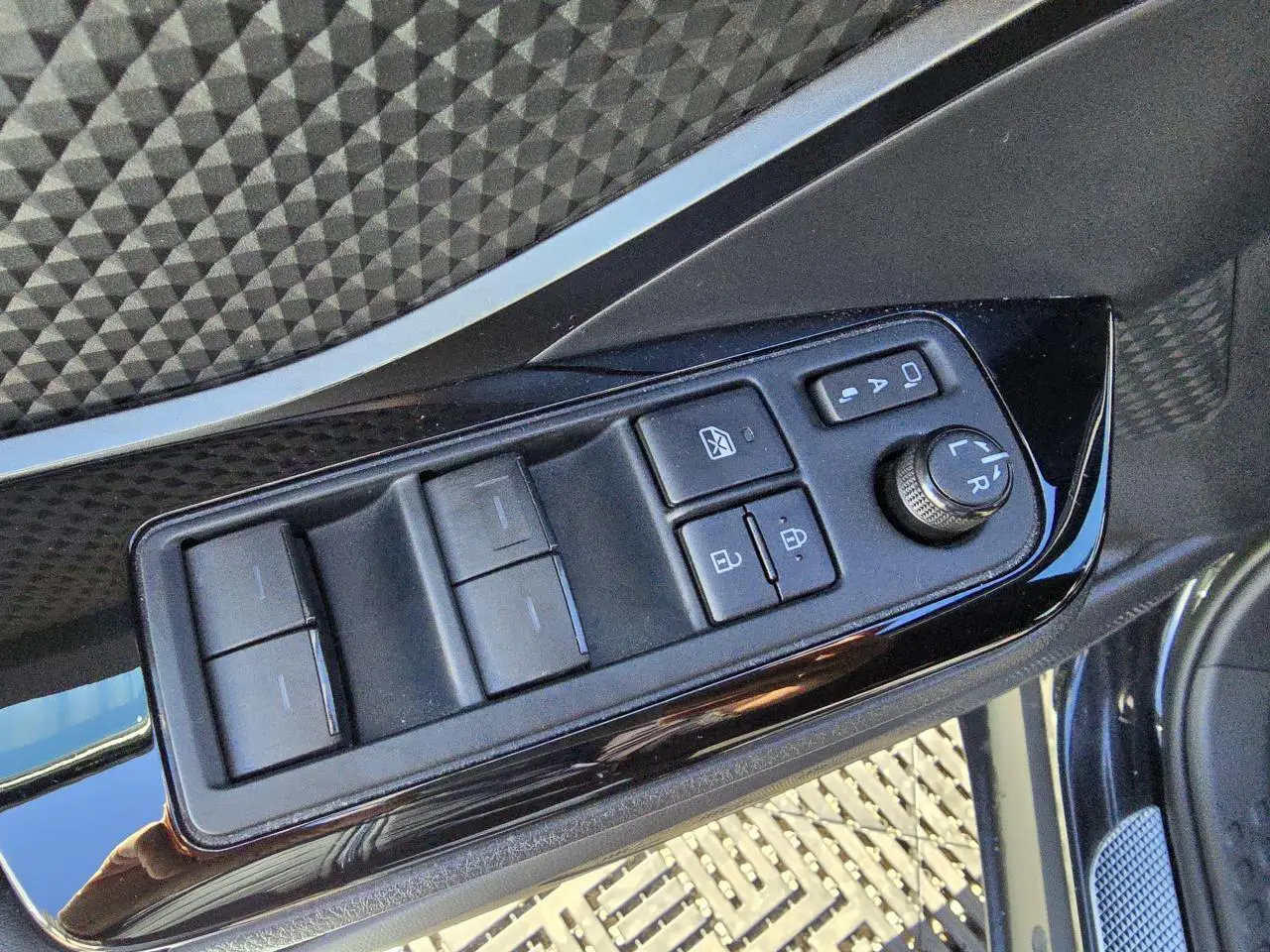 Panneau de commandes des vitres et rétroviseurs côté gauche sur porte noire métallisée d'un Toyota C-HR 2023.