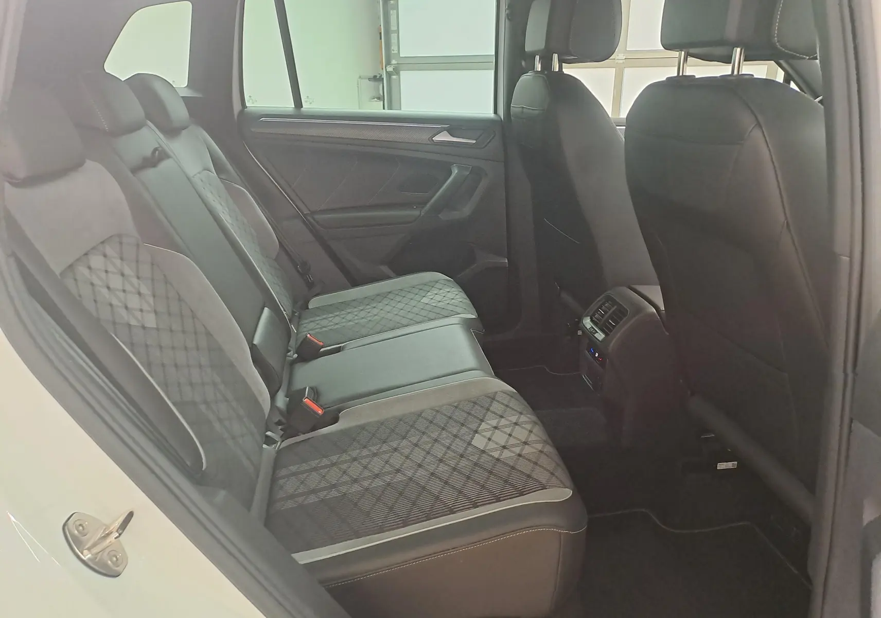Vue intérieure côté gauche des sièges arrière en tissu et cuir noir du Volkswagen Tiguan 1.4 eHybrid blanc pur 2023 R-Line.