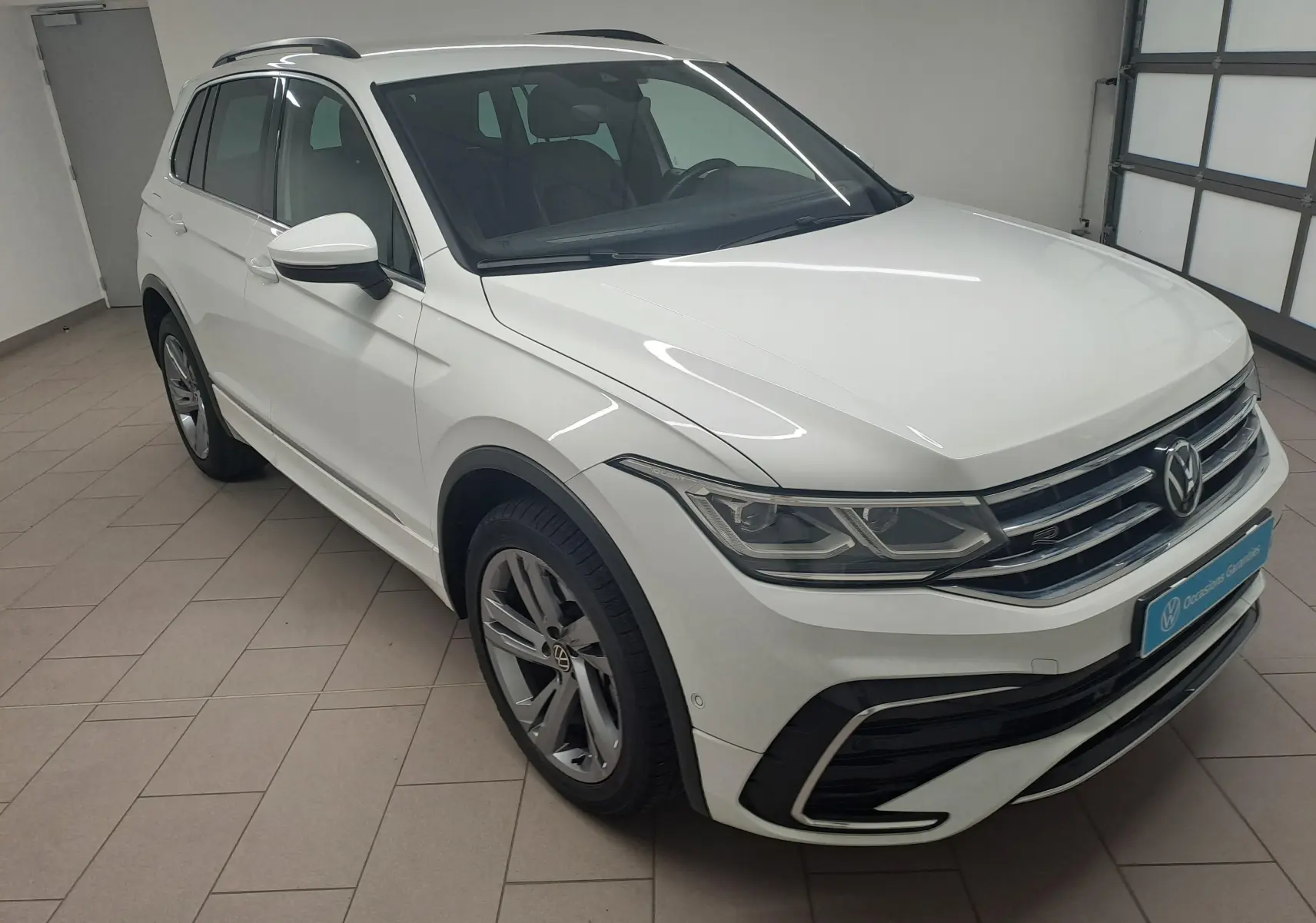 Volkswagen Tiguan 1.4 eHybrid R-Line blanc pur vu en 3/4 avant droit dans un garage lumineux.