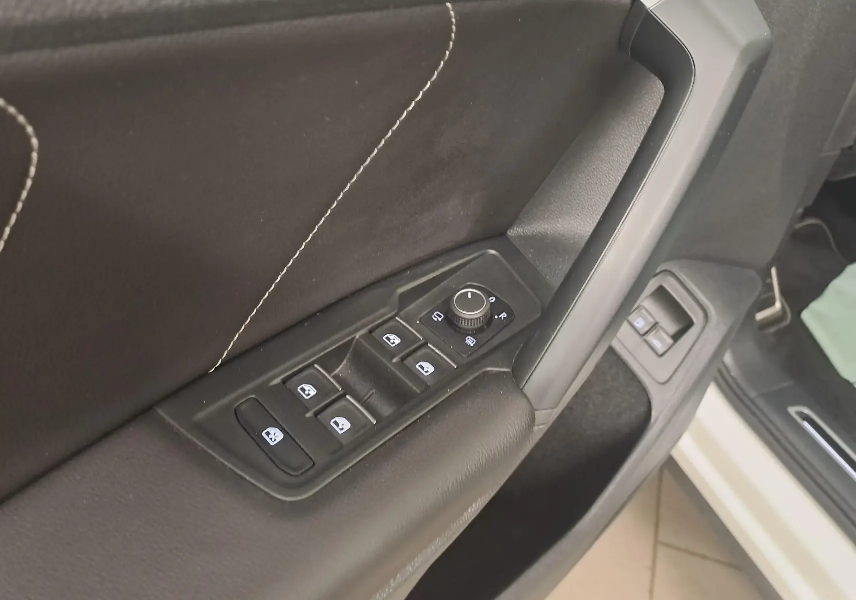 Gros plan sur la commande des vitres et rétroviseurs côté gauche d’un Volkswagen Tiguan blanc pur 2023 R-LINE.