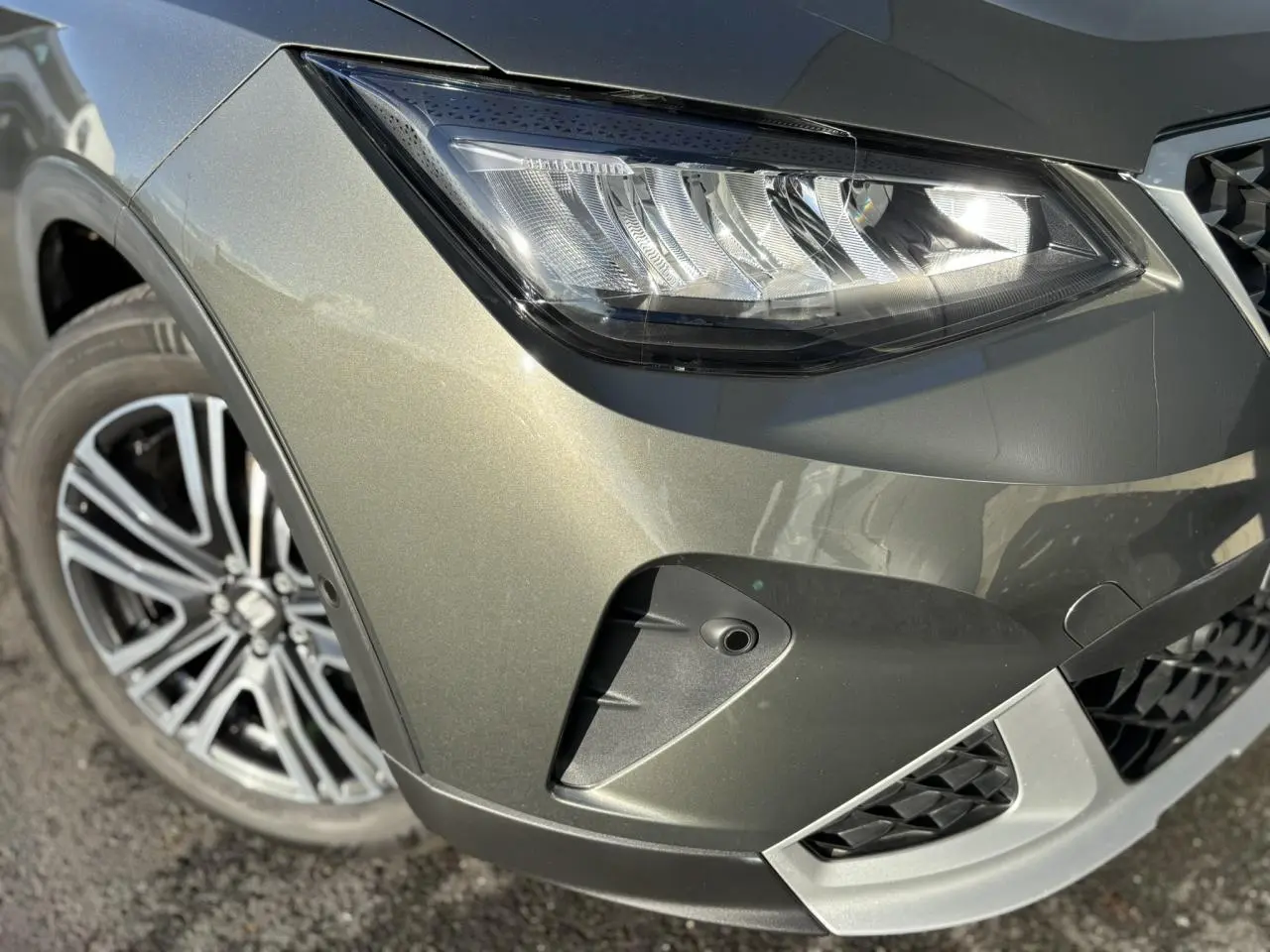 Gros plan sur l'avant droit gris Cliff du SEAT Arona 2025, mettant en valeur le phare LED et la jante alliage 17 pouces.