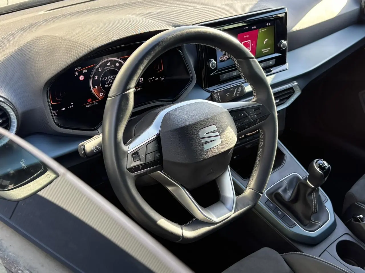 Vue rapprochée de l'intérieur du SEAT Arona TSI 115 Xpérience 2025, volant cuir multifonction et levier de vitesse manuel visibles.