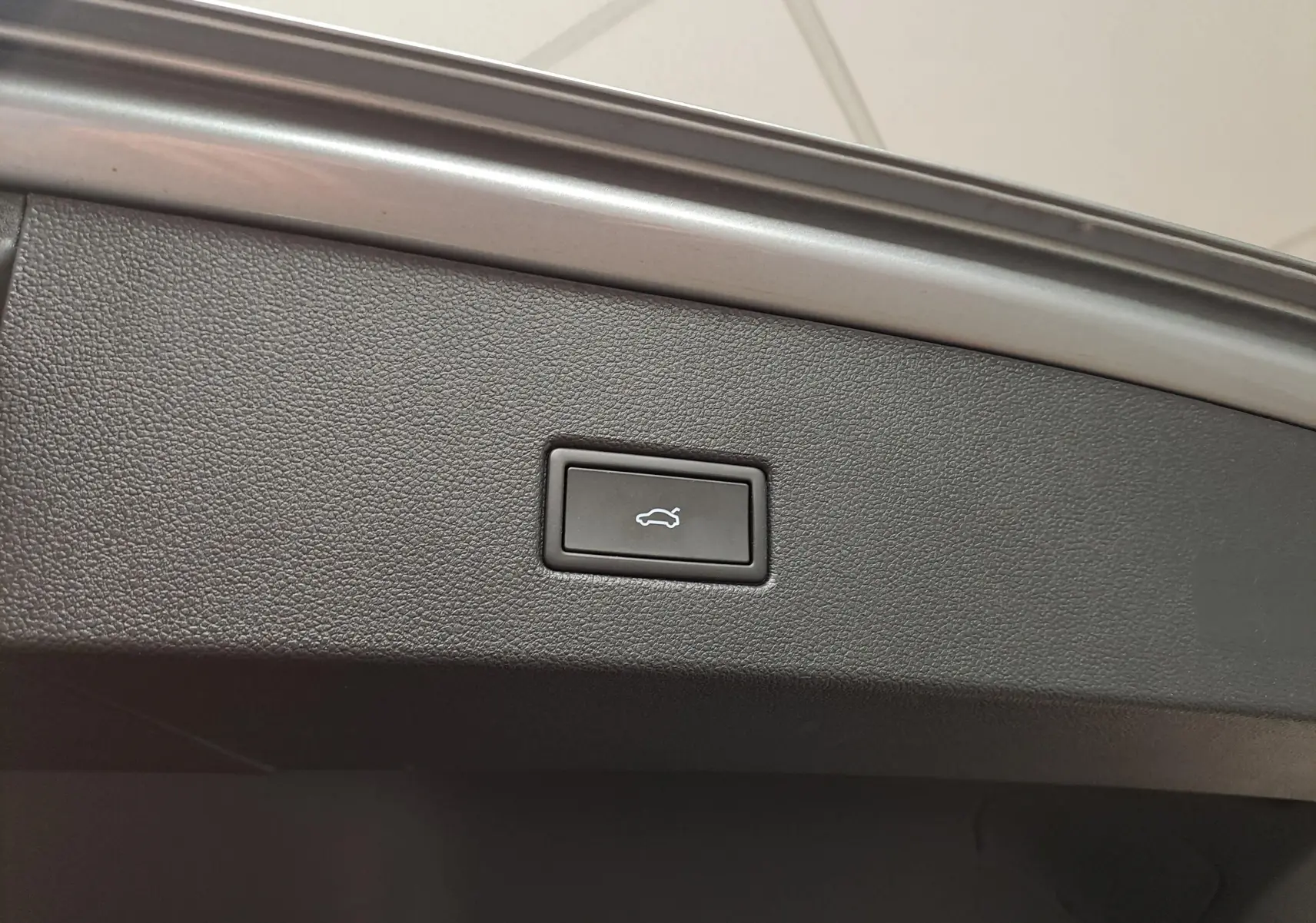 Bouton d'ouverture électrique du coffre sur la partie intérieure du hayon du Volkswagen T-Roc gris Pyrite.