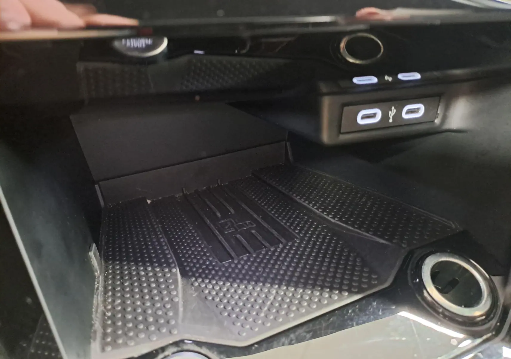 Gros plan intérieur sur la console centrale du Volkswagen T-Roc 2025, montrant la zone de recharge et ports USB éclairés.