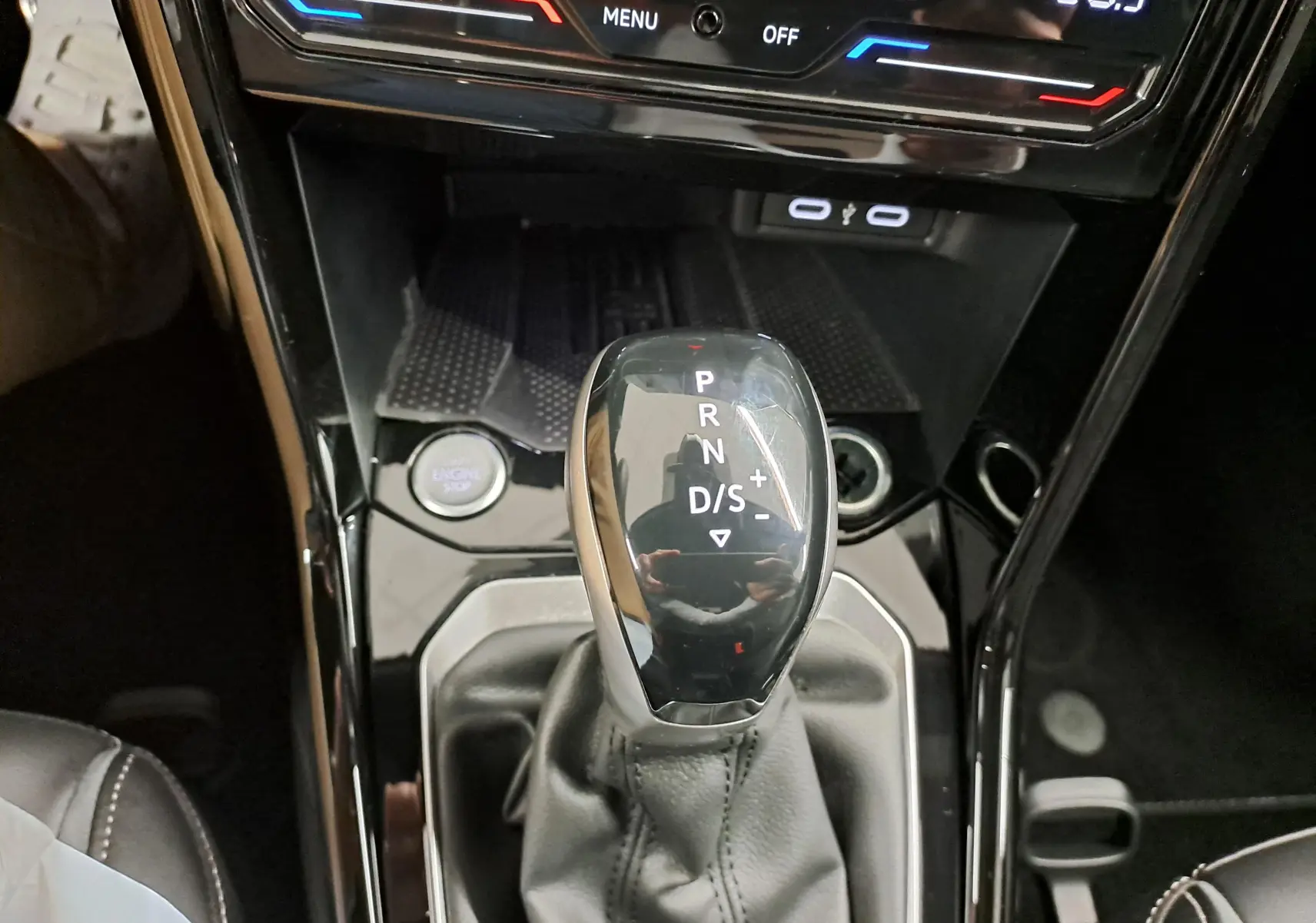 Gros plan sur le levier de vitesses de la boîte auto du Volkswagen T-Roc 1.5 TSI 2025, intérieur noir brillant.