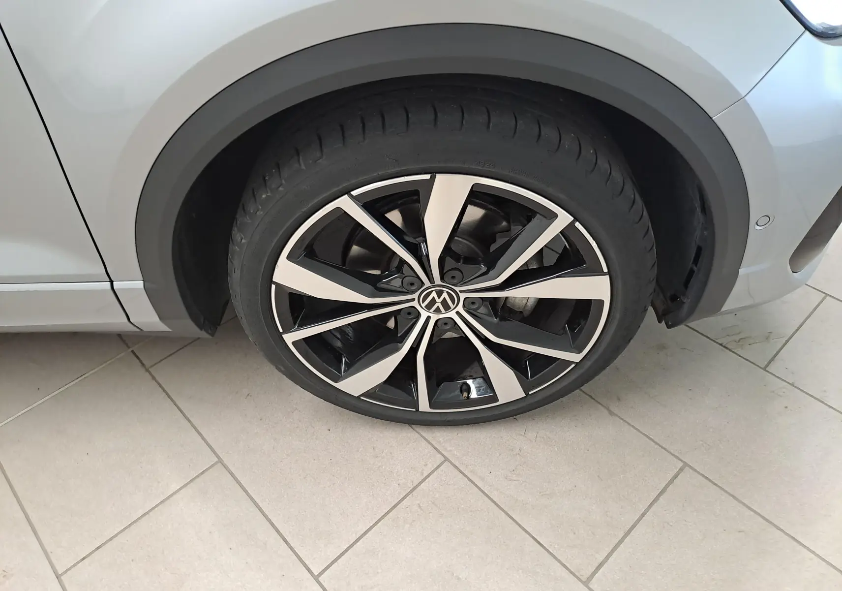 Gros plan sur la jante noire et argentée 19'' Misano du côté avant droit du Volkswagen T-Roc gris pyrite.