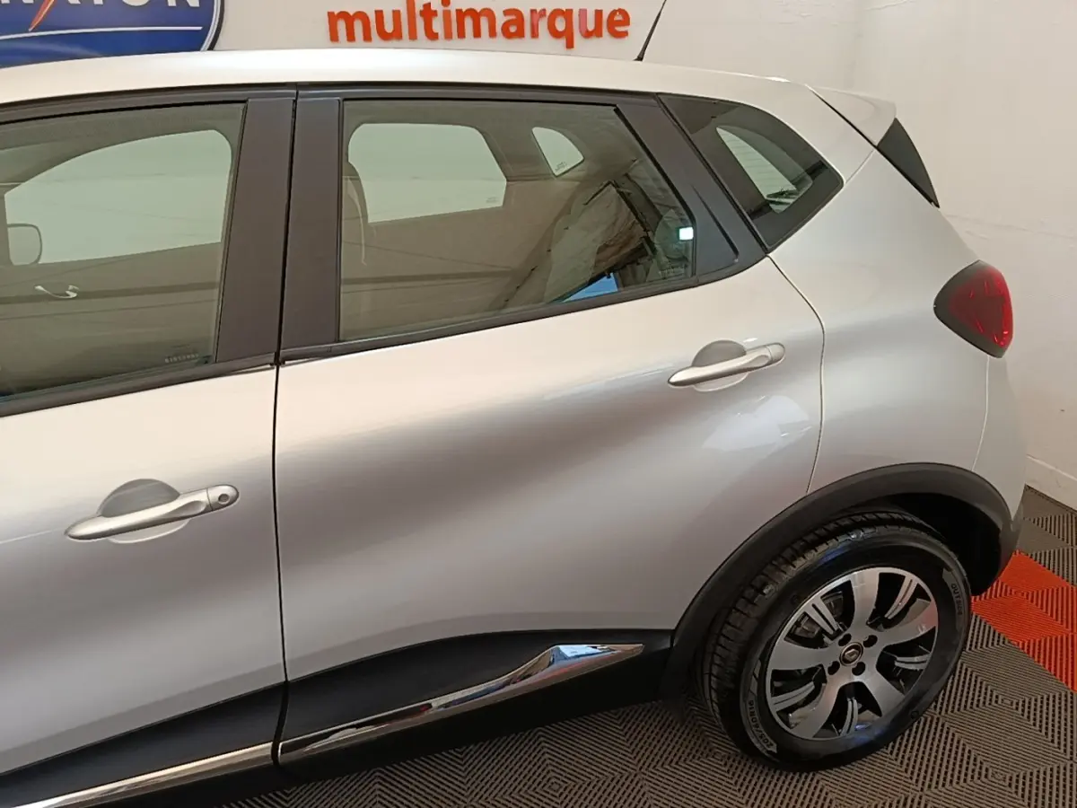 Vue latérale droite d'un Renault Captur gris clair, mettant en valeur la porte arrière et la roue arrière avec jante stylisée.