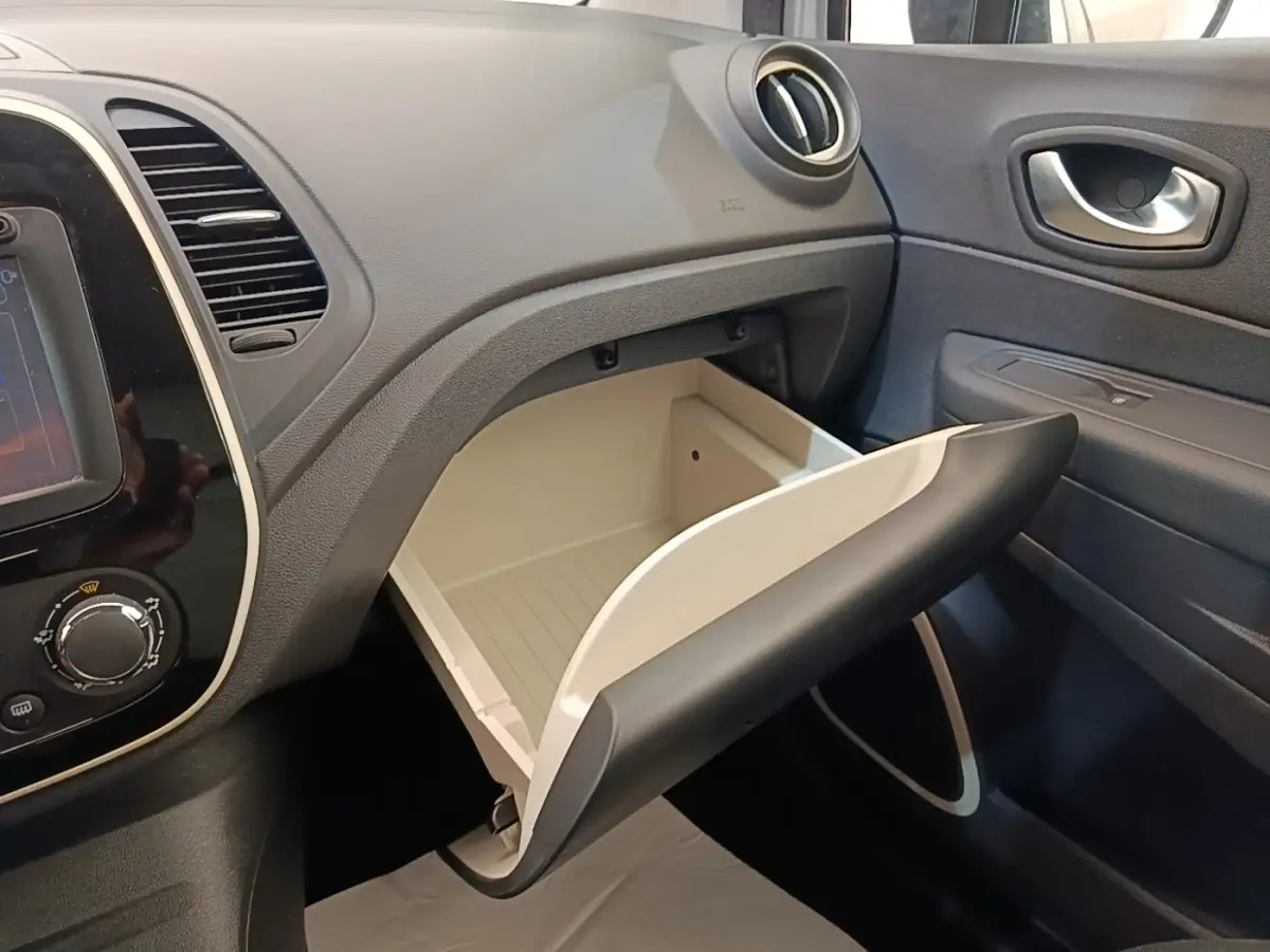 Vue intérieure côté passager du coffre à gants ouvert du Renault Captur Zen TCe 90 gris clair, avec tableau de bord noir.
