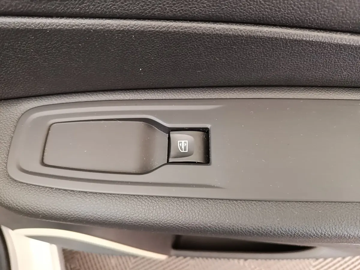 Gros plan sur le bouton de commande de la vitre électrique côté conducteur du Renault Captur gris clair 2018.
