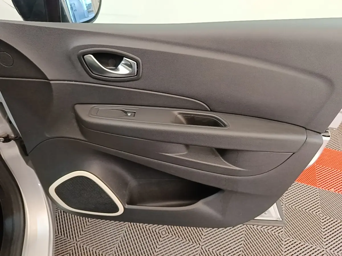 Vue rapprochée de la porte intérieure côté conducteur du Renault Captur gris clair avec haut-parleur intégré et poignée argentée.
