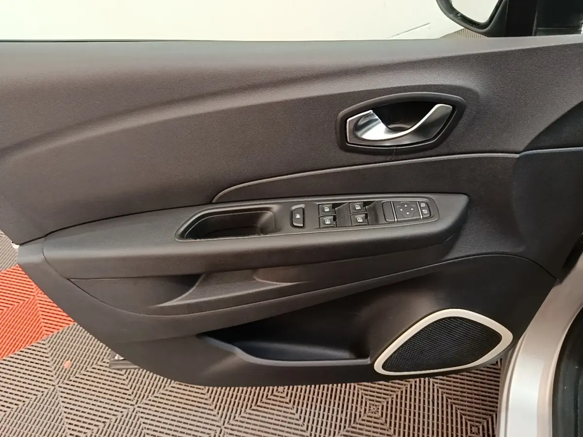 Vue rapprochée de la porte avant gauche du Renault Captur gris clair, avec commandes électriques et poignée argentée.