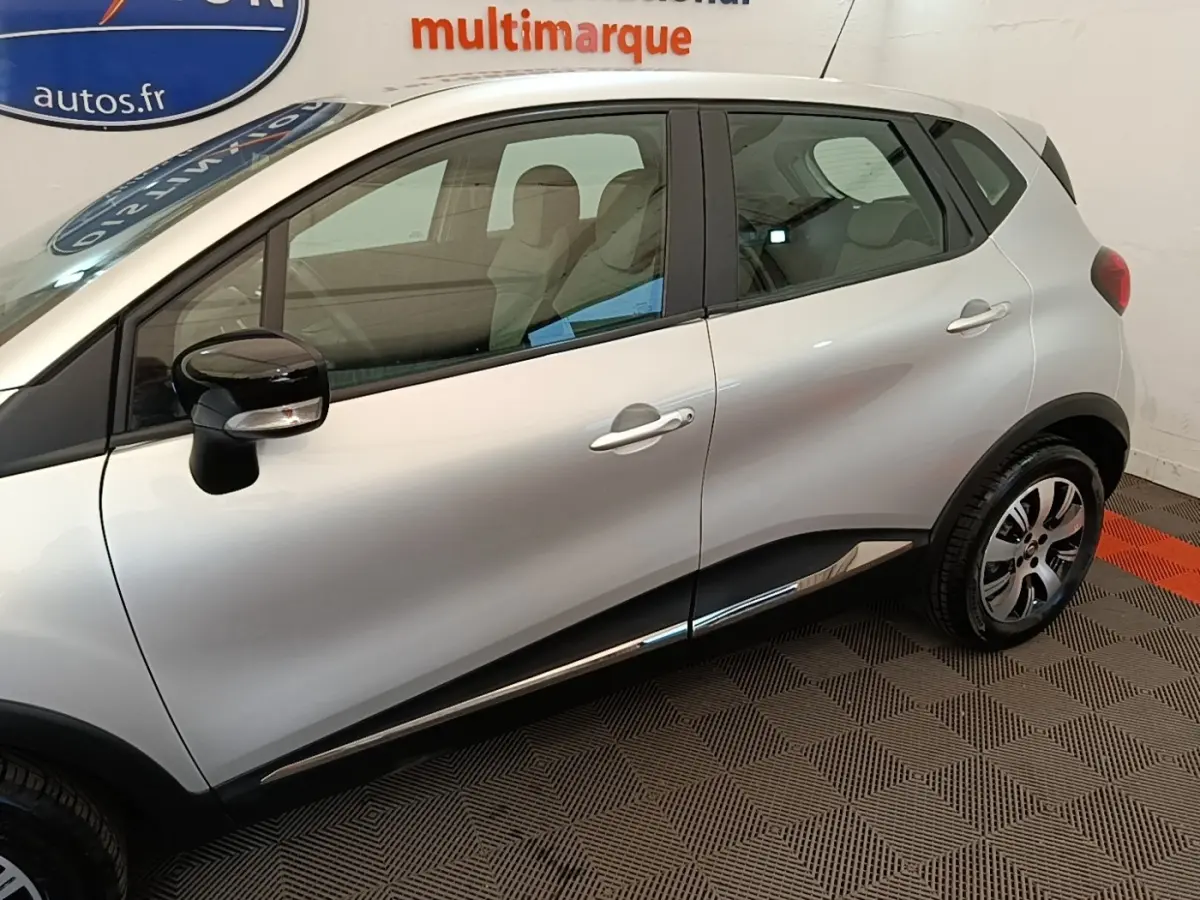 Vue latérale côté gauche d’un Renault Captur gris clair 2018 avec rétroviseurs noirs et jantes alliage.
