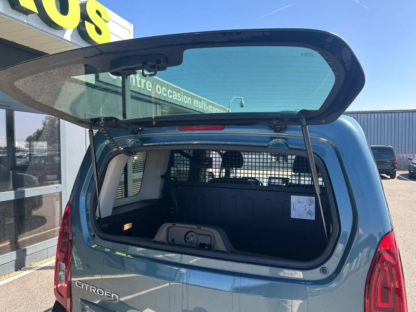 Coffre ouvert en vue arrière d’un Citroën Berlingo Kiama Blue avec cloison de séparation visible.