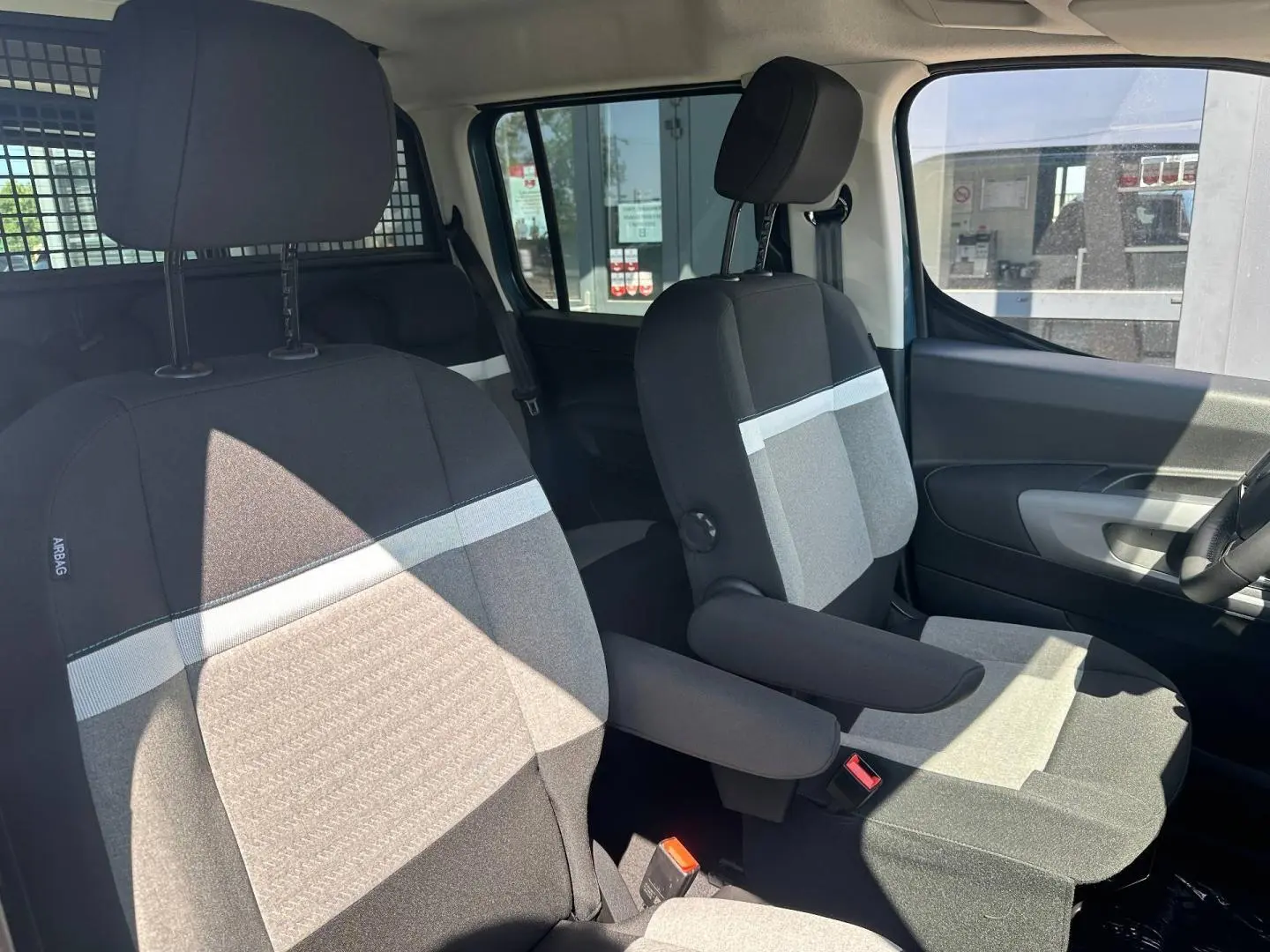 Intérieur de la Citroën Berlingo 2026 en Kiama Blue, vue côté droit sur les sièges avant gris avec accoudoirs.