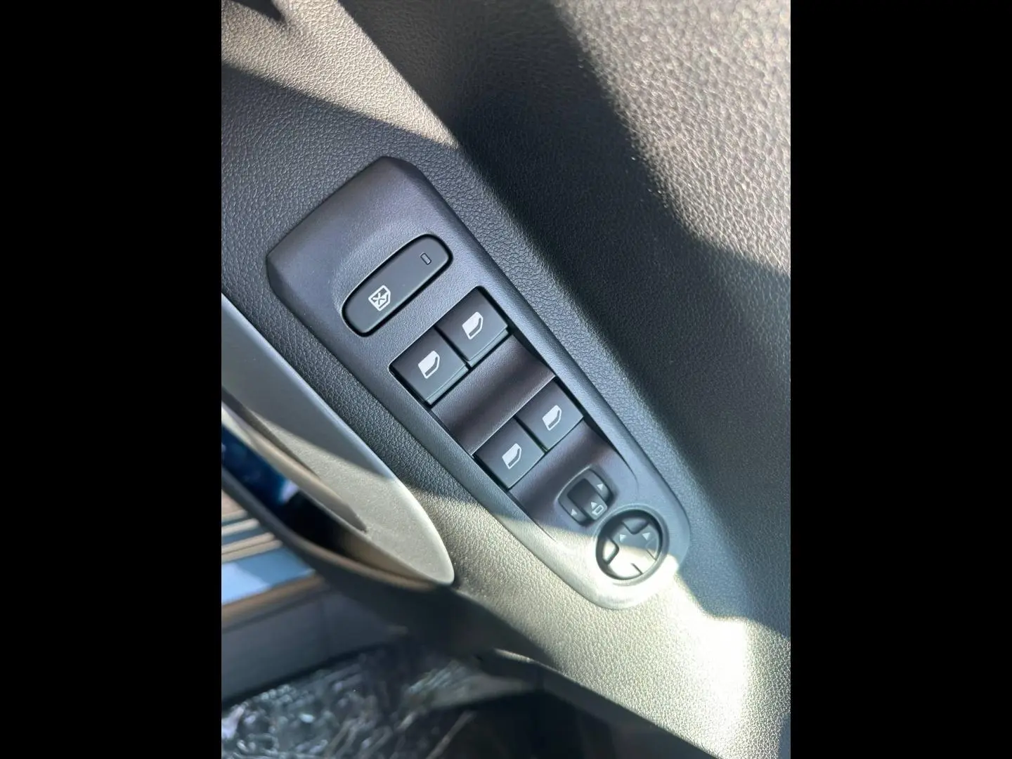 Gros plan sur les commandes des vitres électriques et rétroviseurs sur la porte côté conducteur d’un Citroën Berlingo bleu Kiama.