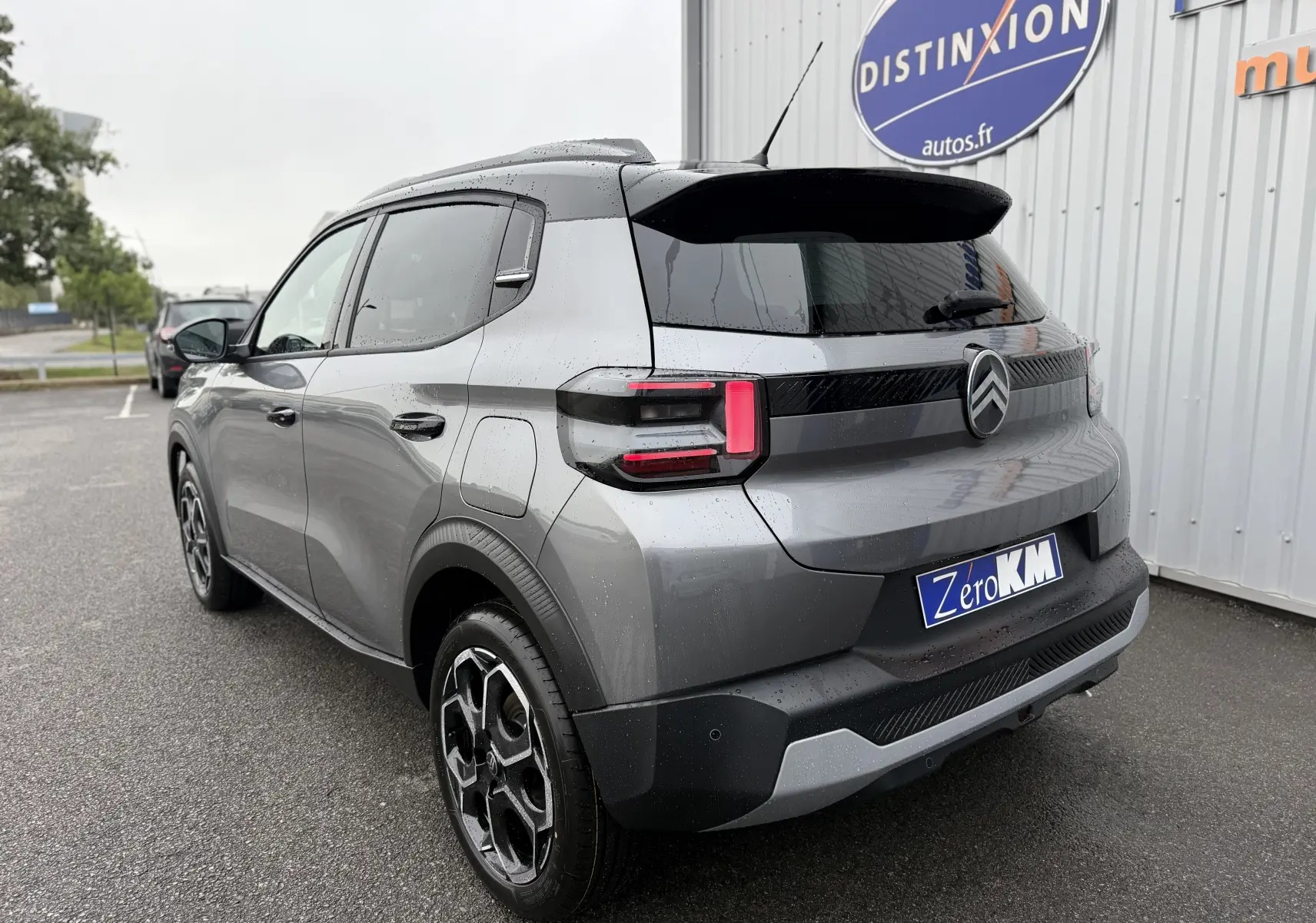 Vue 3/4 arrière droite d'une Citroën C3 hybride gris Mercury avec toit noir et feux arrière LED distinctifs.
