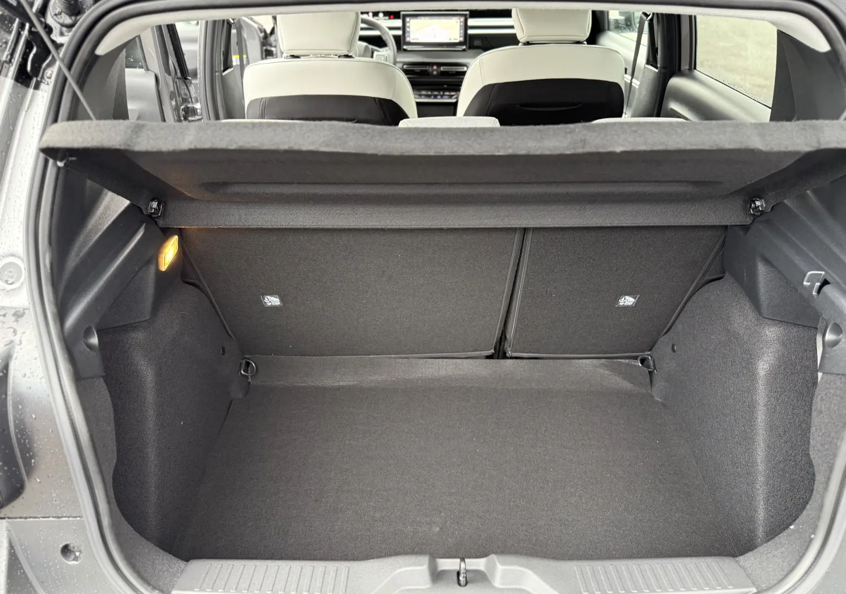 Coffre ouvert vu de l’arrière d’une Citroën C3 hybride gris Mercury avec intérieur clair et tablette de séparation.