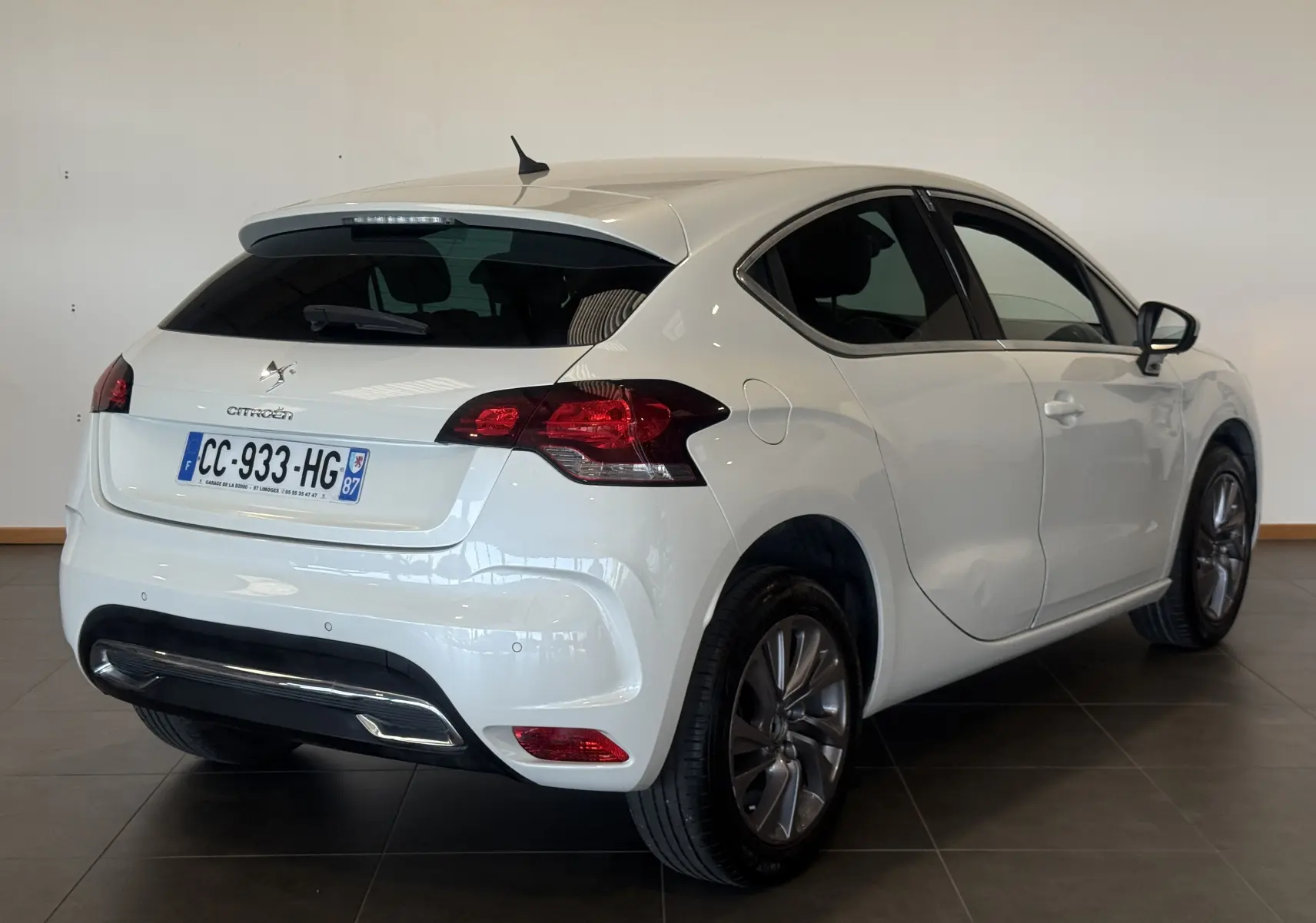 Vue 3/4 arrière droite d'une Citroën DS4 blanche de 2012, avec feux arrière rouges et jantes alliage foncé.